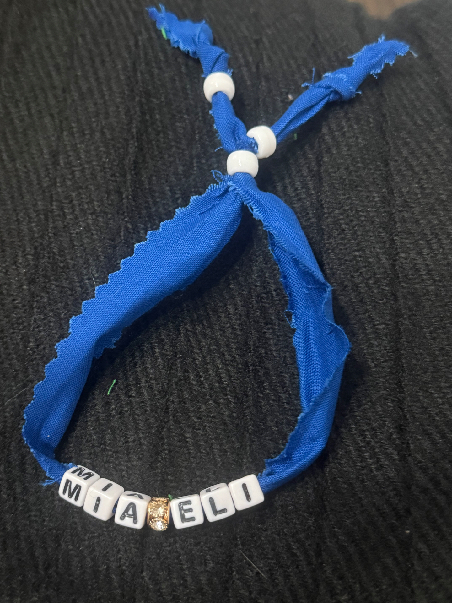 Blue fabric bracelet with MIA and ELI letter beads and a gold sparkle bead