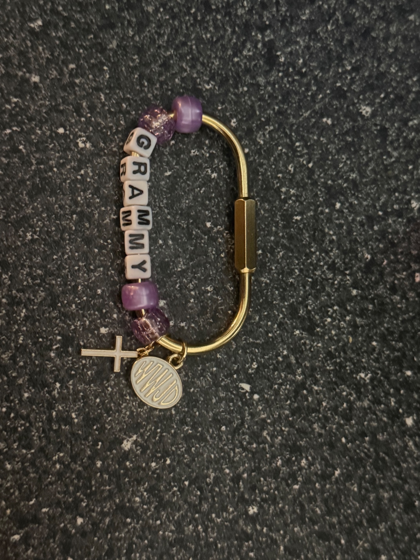 Gold bag clip spelling GRAMMY with purple beads, a cross and a WWJD charm