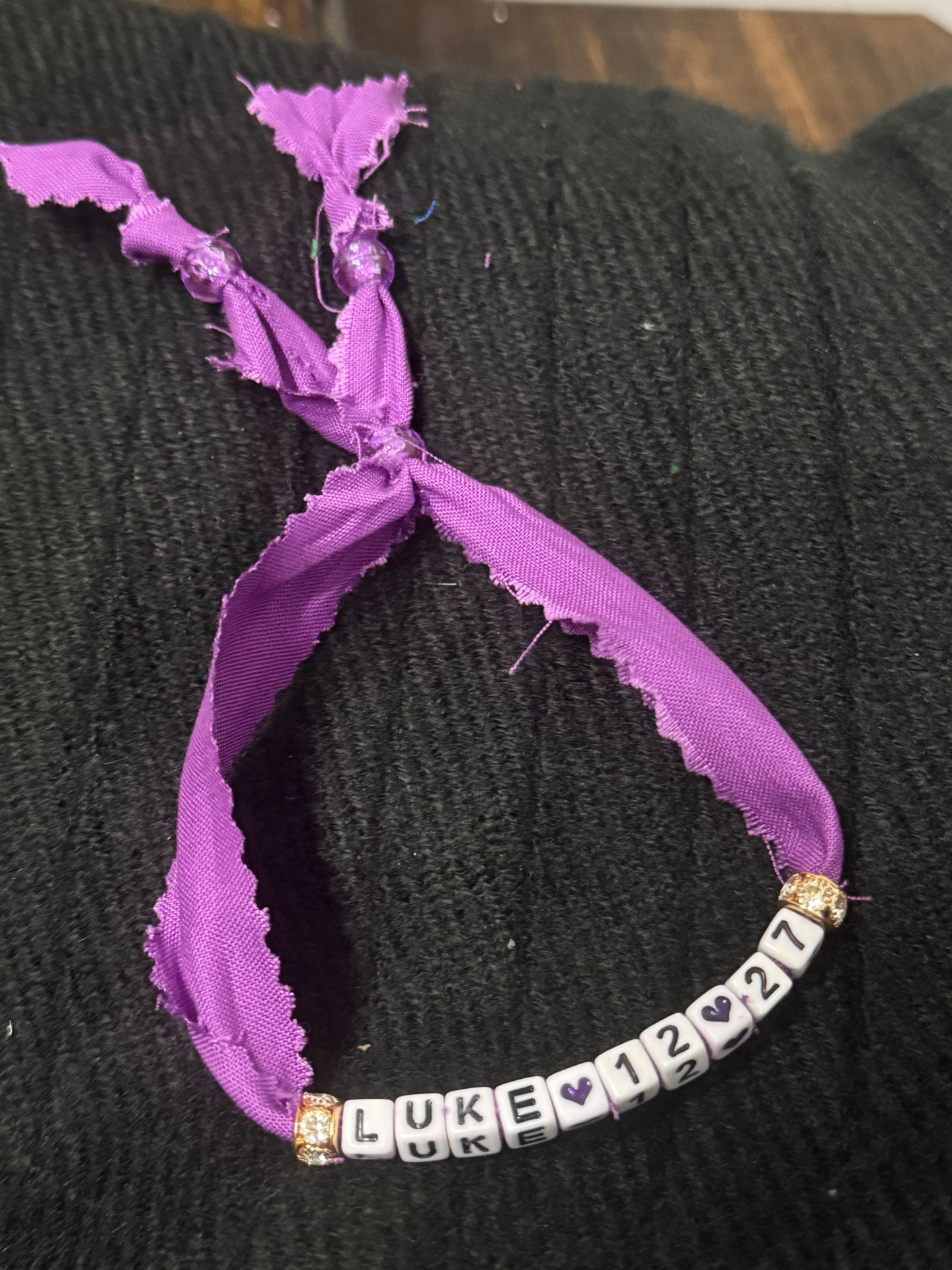 Purple fabric bracelet with LUKE 12:27 in letter beads