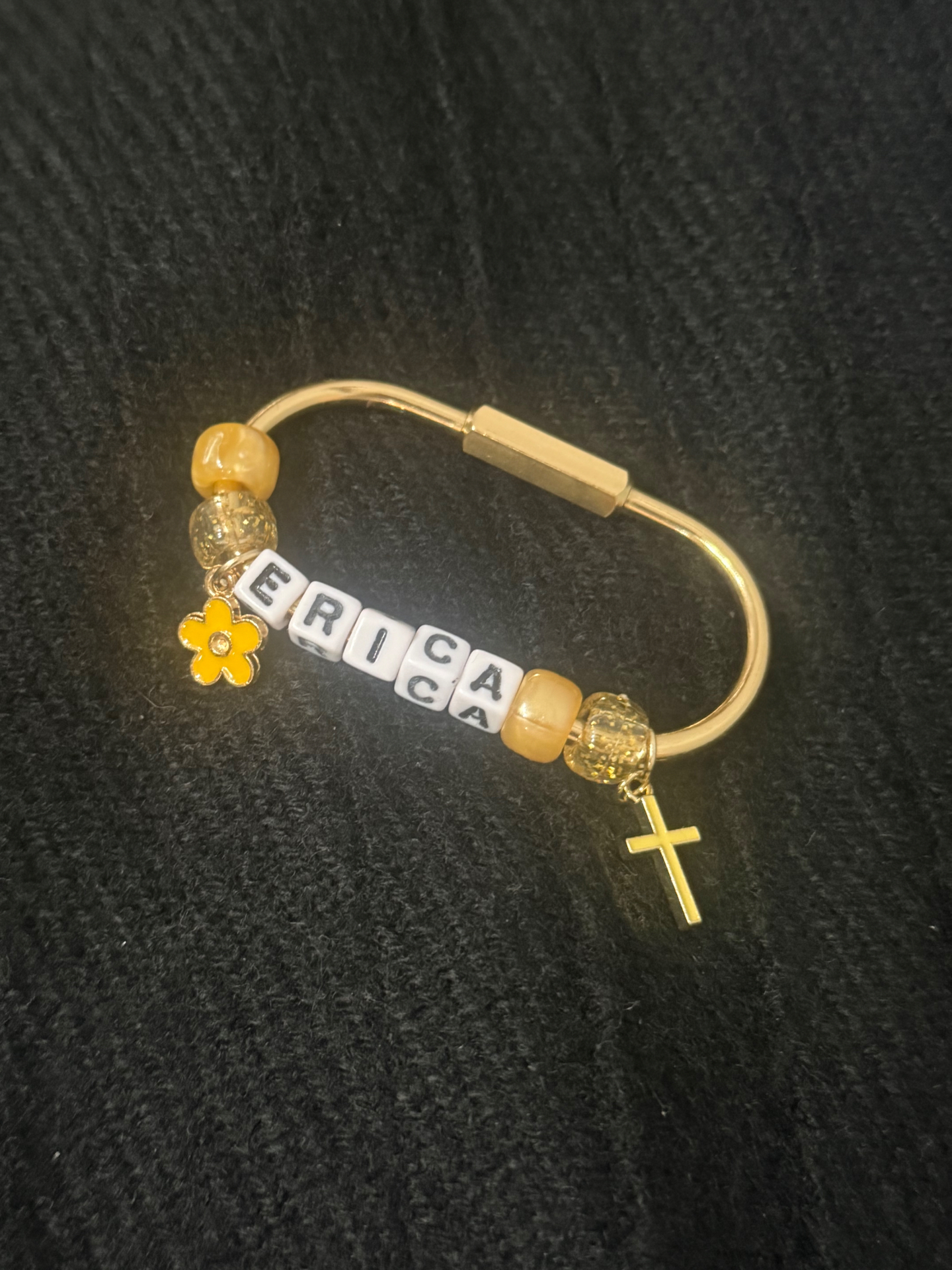 Gold bag clip spelling ERICA with yellow beads, a flower charm and a cross charm