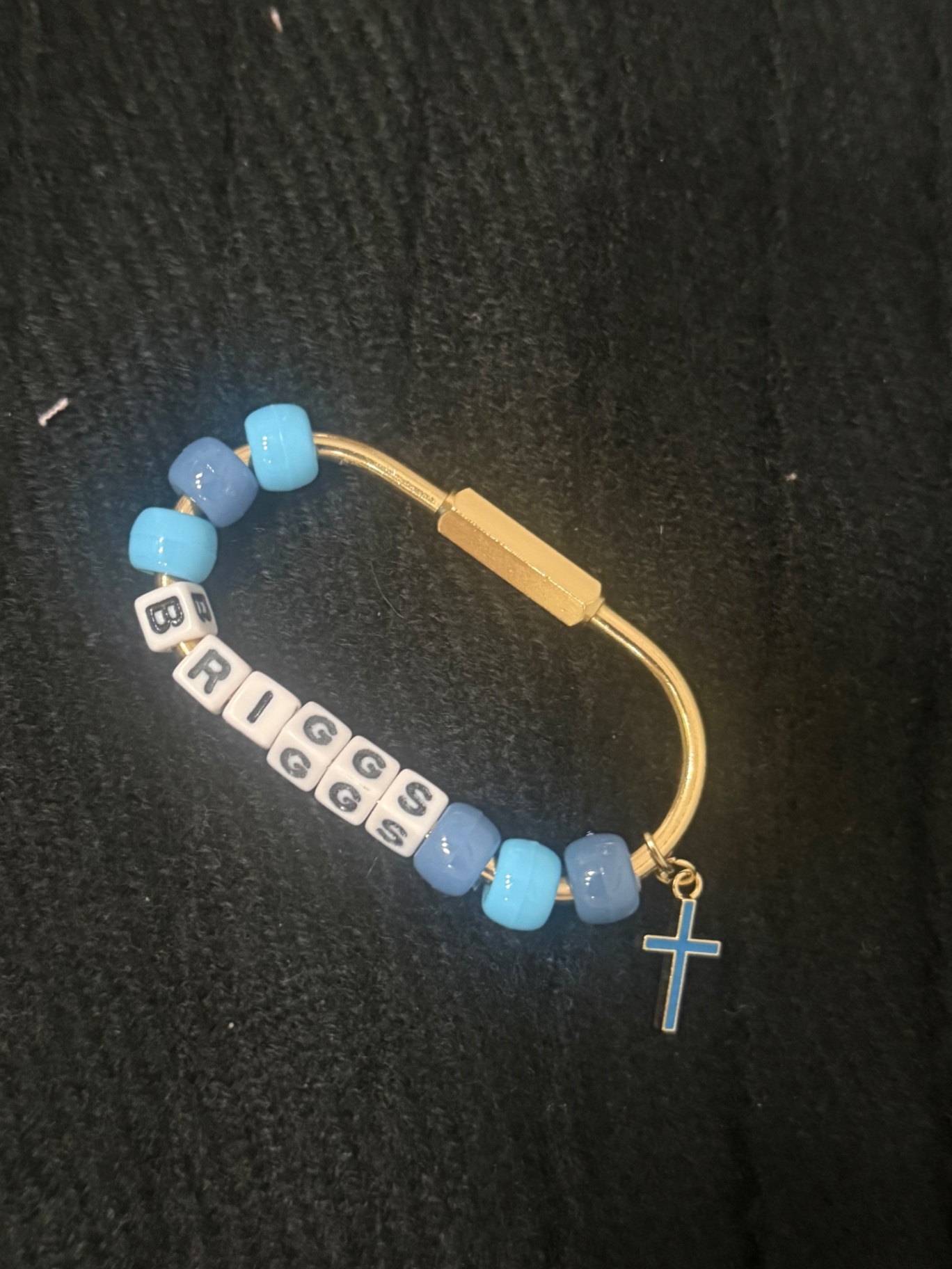 Gold bag clip with the name BRIGGS in letter beads, blue beads and a blue cross charm